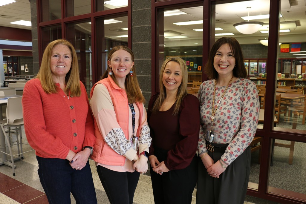 A group of woman standing in front of a school library.