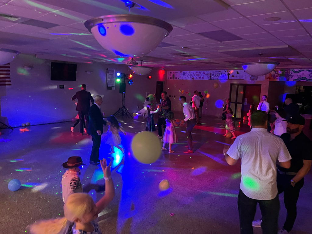 Young students and adults dancing at a glow-in-the-dark dance.