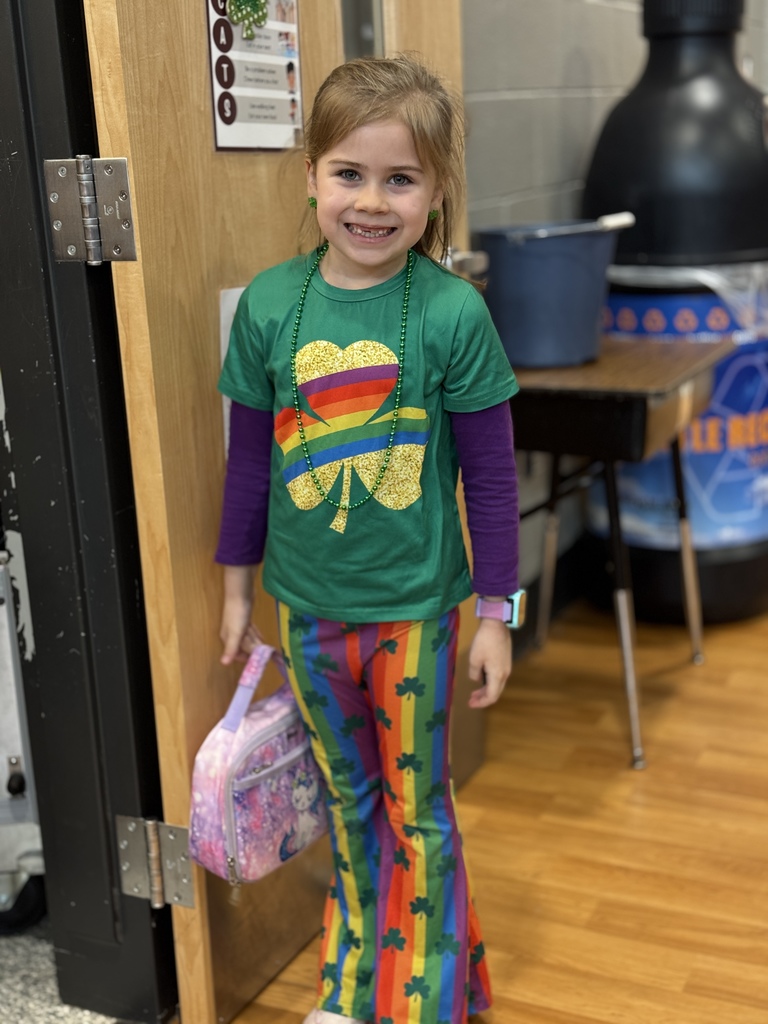 A young girl in a green shirt and rainbow pants for St. Patrick's Day.