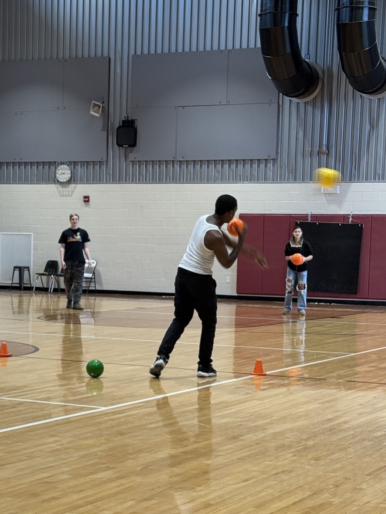 Students play dodgeball together indoors.