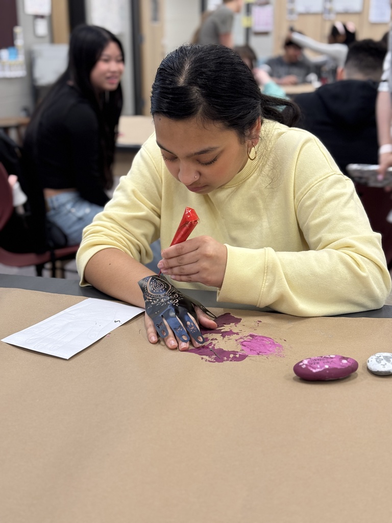 A student paints Henna on her hand.