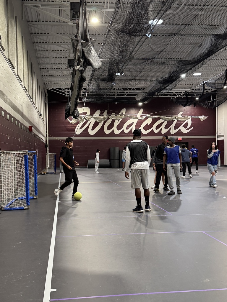 Students play soccer together indoors.