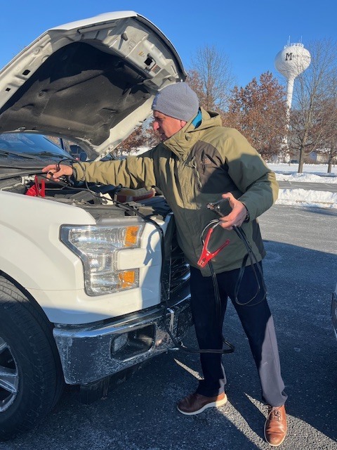 A man attaches jumper cables to a truck battery.
