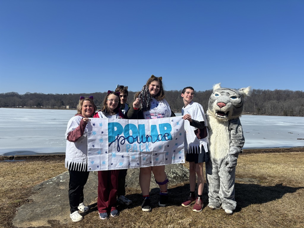 Staff and students stand in front of a lake that is frozen over.