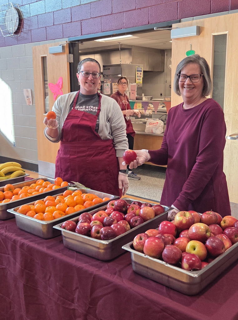 Staff serving fruit to students.