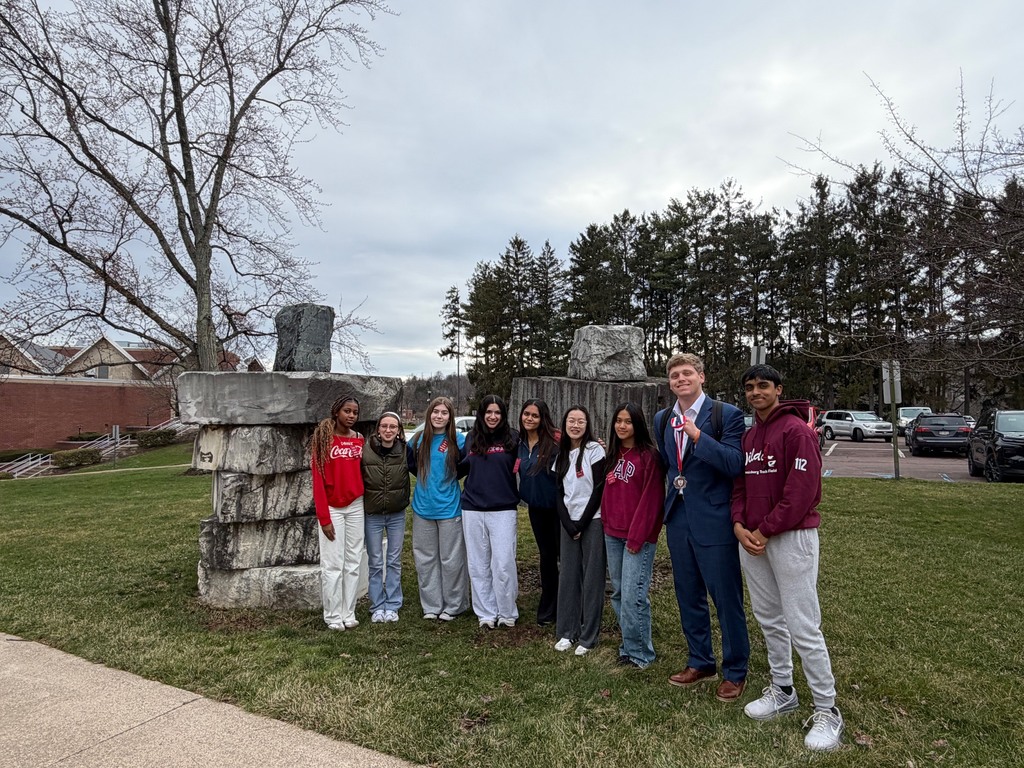 A group of high school students standing outdoors in front of a rock formation.