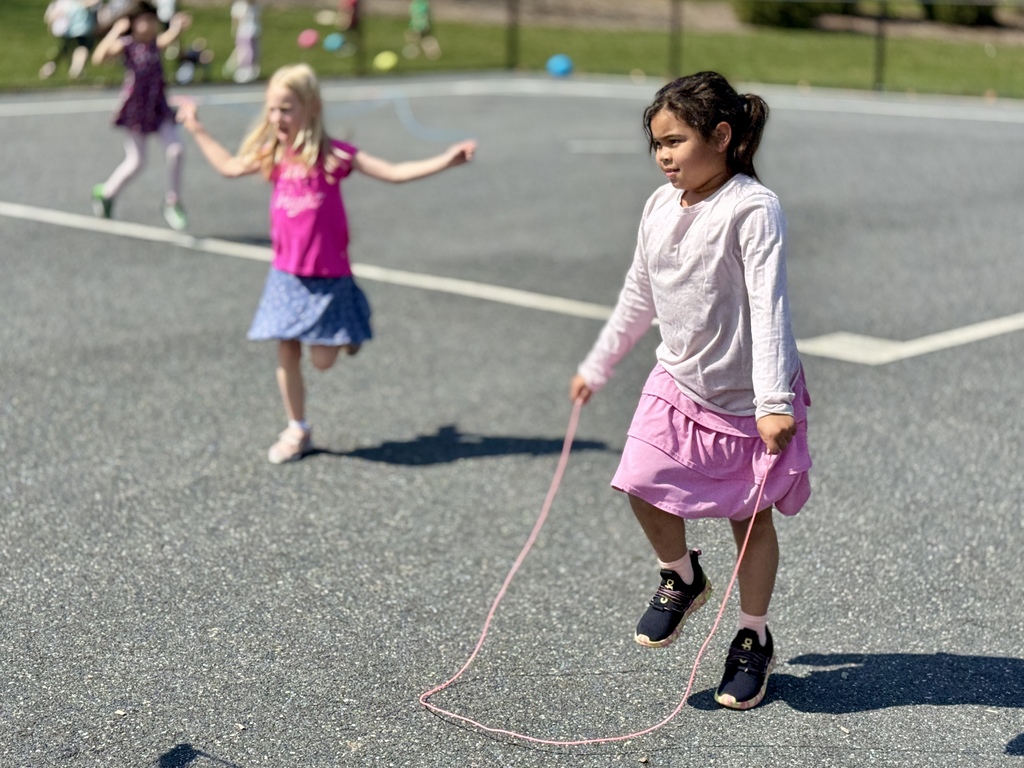 Two happy young girls jumping rope during recess.
