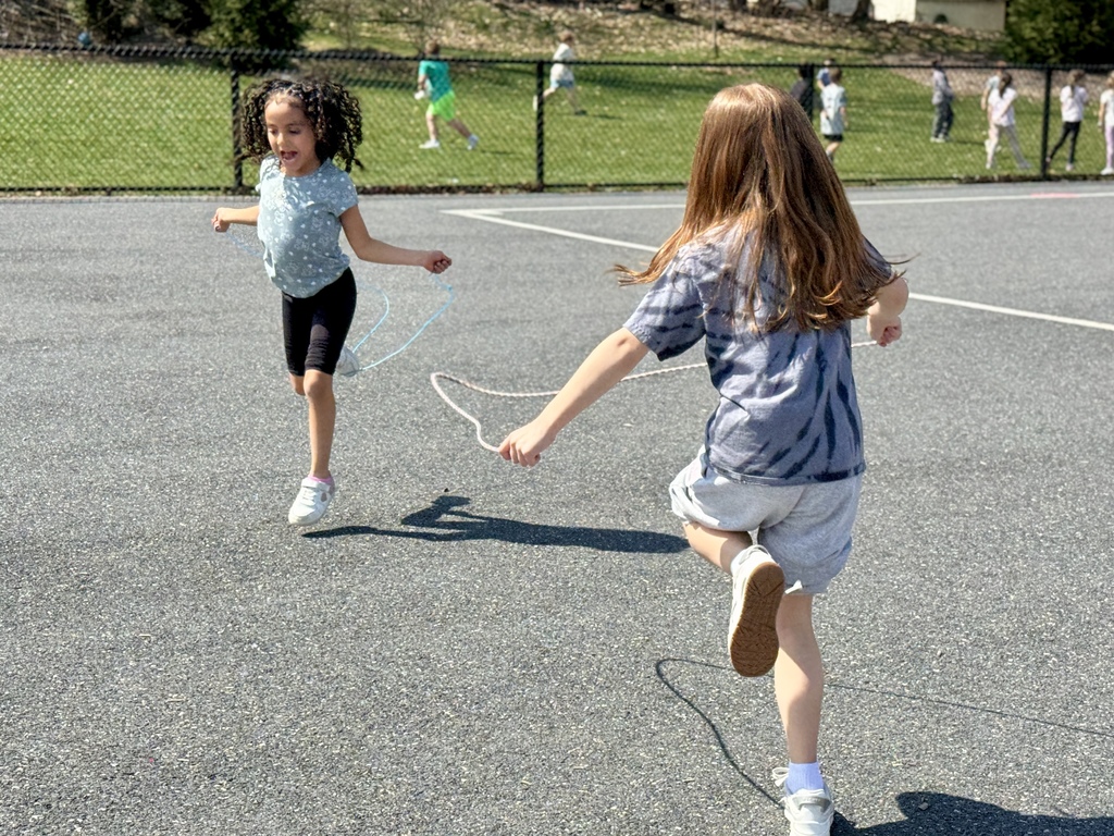 Two happy young girls jumping rope during recess.