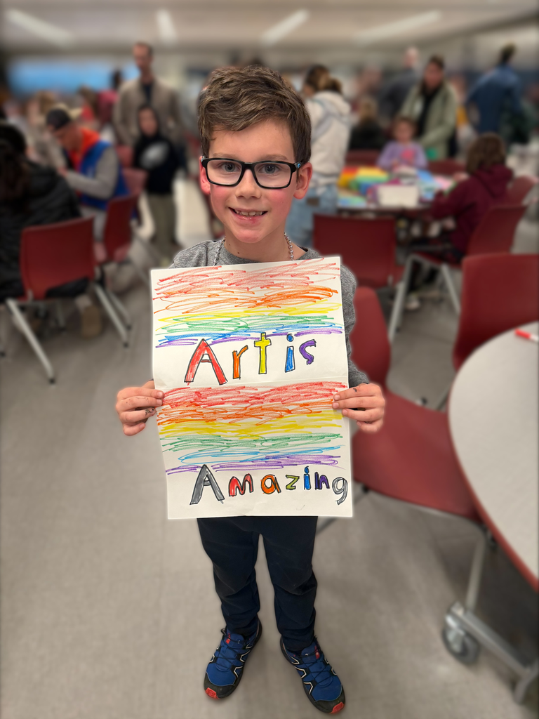 A young boy holding a sign that says Art is Amazing.