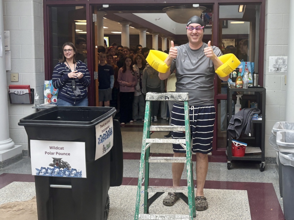 A man wears arm floaties and goggles while preparing to jump into a bucket of ice water.