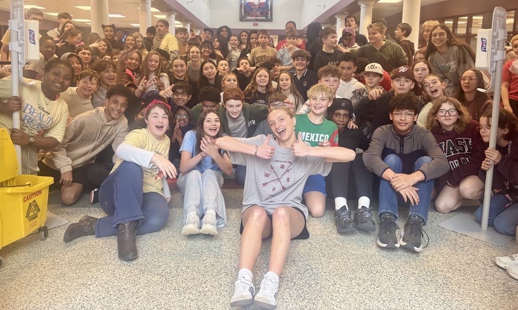 A woman gives a thumbs up while sitting with a large group of students.