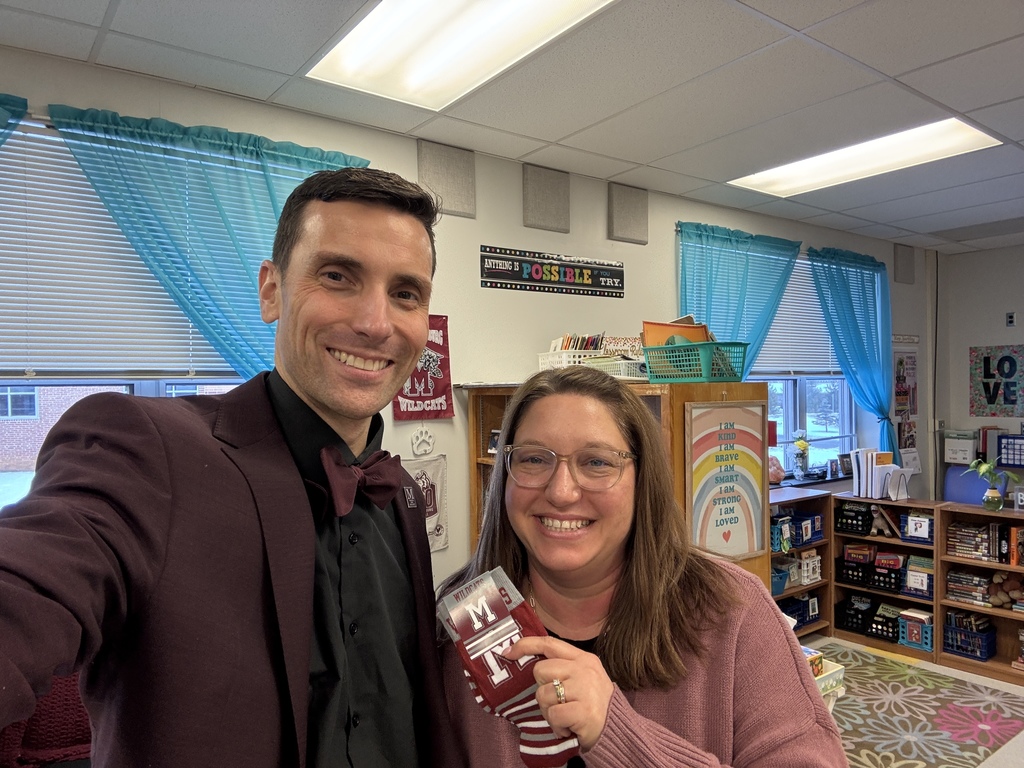 Two adults standing next to each other, one holding a pair of branded M socks.