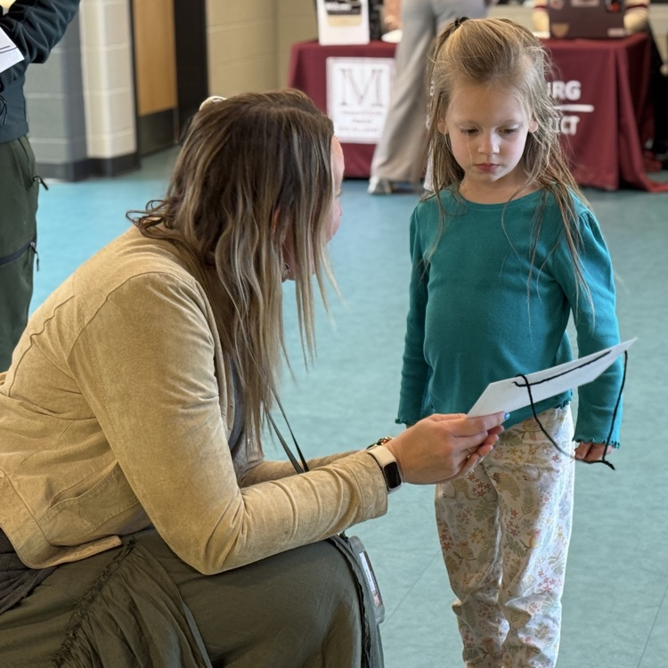 A teacher gives a young girl a name tag.