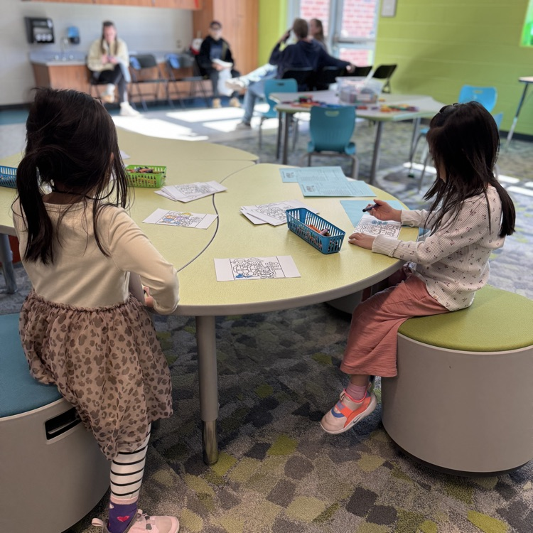 two young students sit at a table in color.