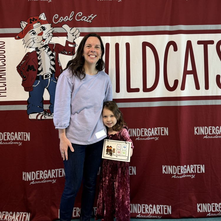 hey Mom and her young daughter standing in front of a wildcat banner