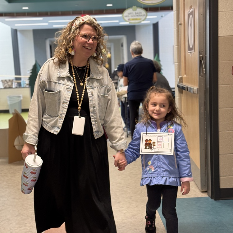 an adult staff member walks a young student down the hallway.