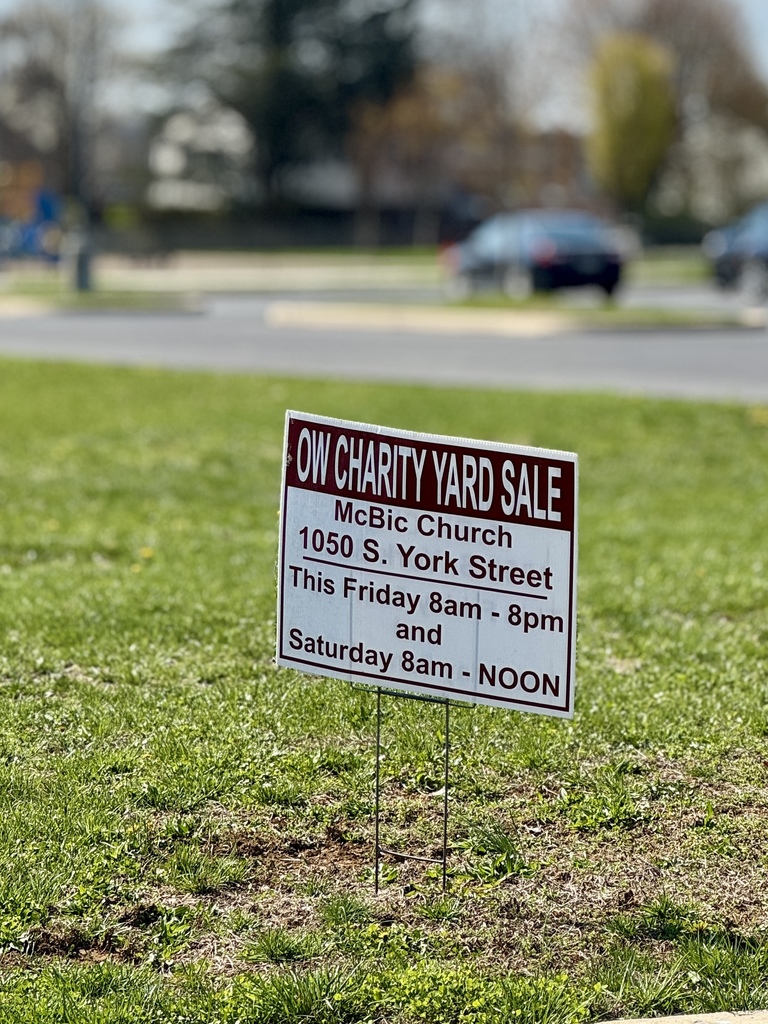 Sign posted in grass that advertises a community yardsale this friday and saturday.