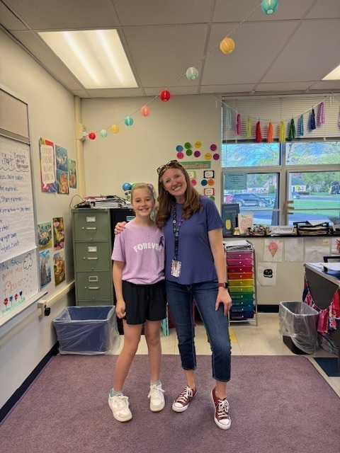 A student and staff member stand next to each other wearing purple for Purple Up! Day.