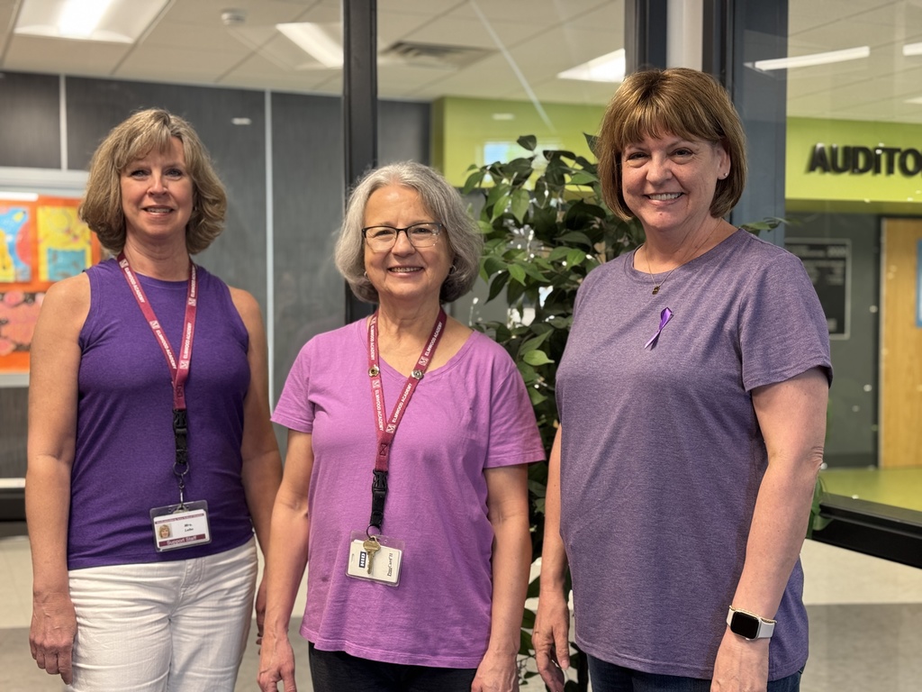 Three staff members in purple for Purple Up! day.