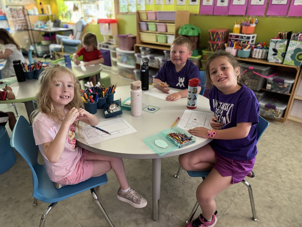 Three young students around a table, all wearing purple for Purple Up! day.