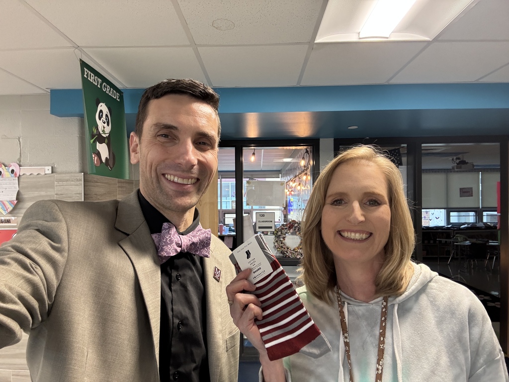 A man and woman smile while holding a pair of branded maroon and gray socks.