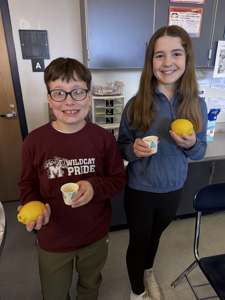 Two students holding a lemon and homemade lemonade.