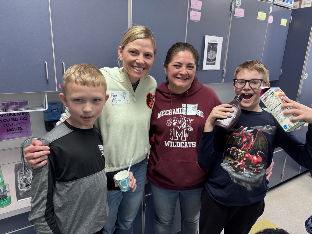 Students and teachers holding homemade ice cream and toppings.