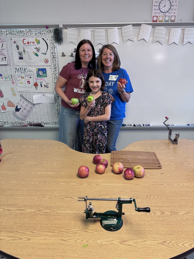 Student and staff standing behind a table of apples.