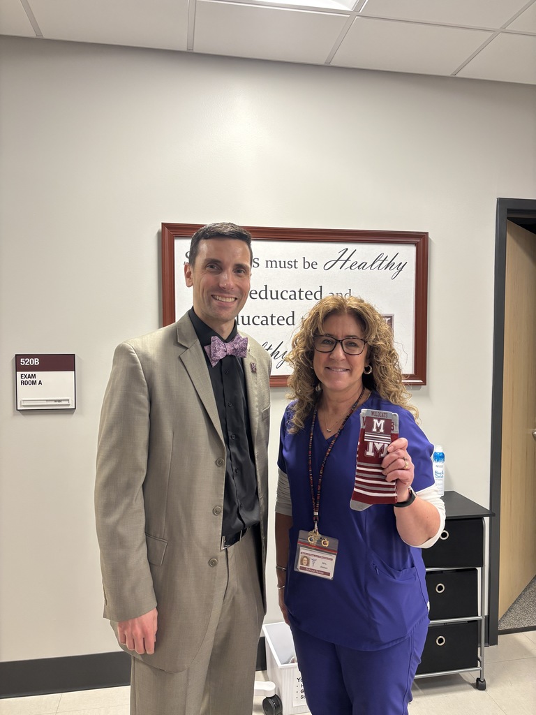 A school nurse in scrubs holding a pair of socks and standing next to a man in a suit.