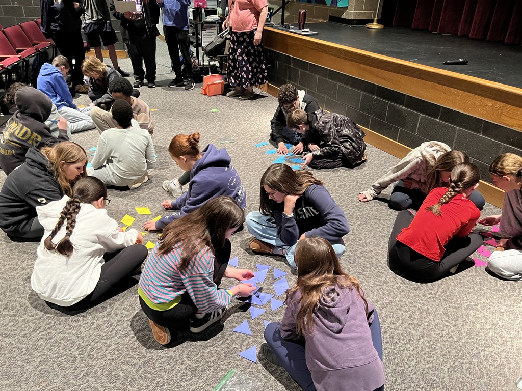 Students on the floor of an auditorium completing a game.