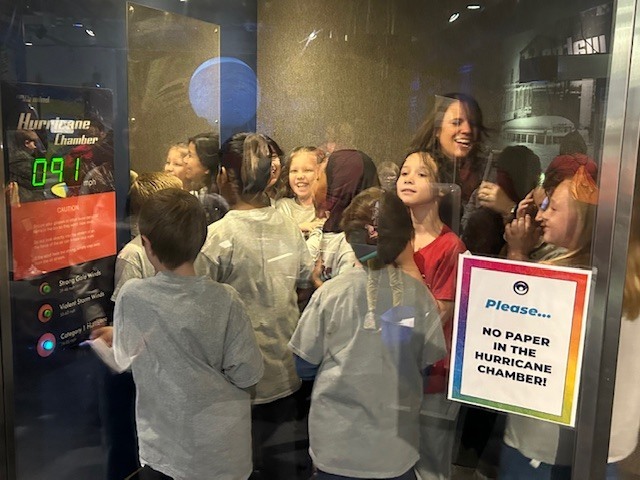 Students piled into a "hurricane chamber" simulator.