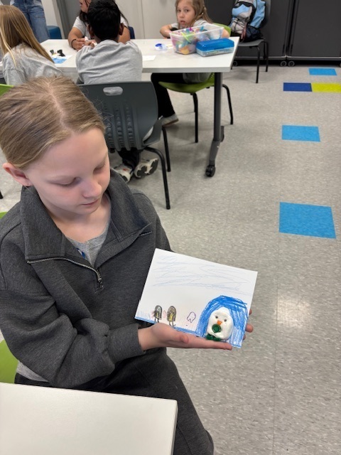 A students shows an art project completed at a hands-on STEM museum.