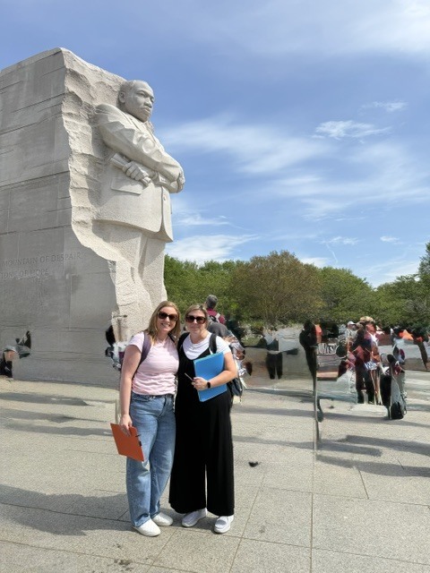 Two people standing in front of a statue in Washington DC.