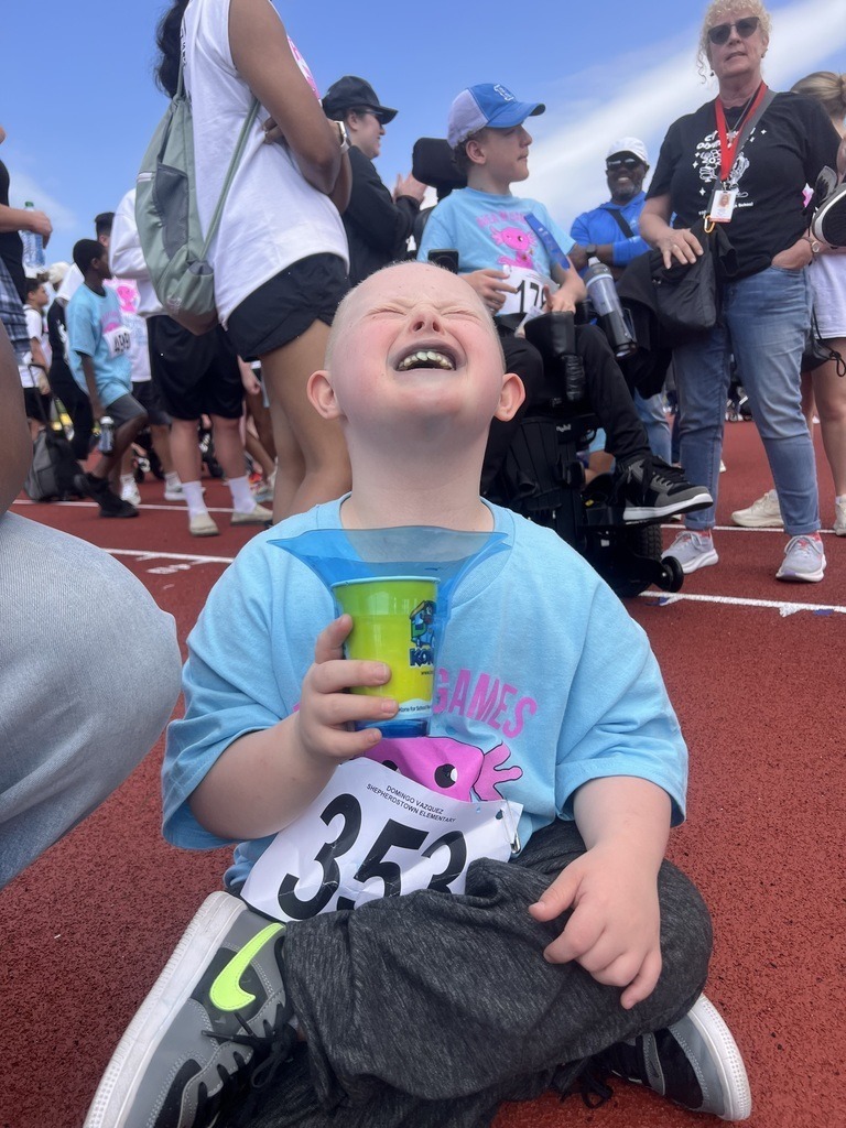 A student sitting on the ground with a huge smile on his face.