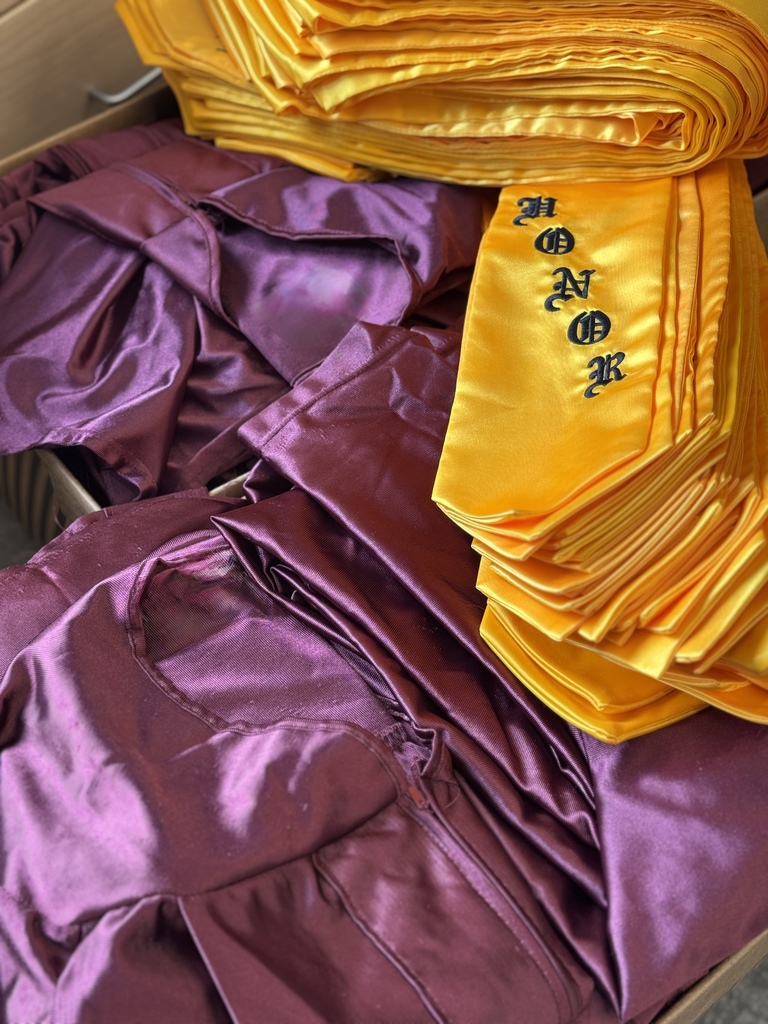 A closeup picture of a maroon graduation gown and yellow "Honor" stole.