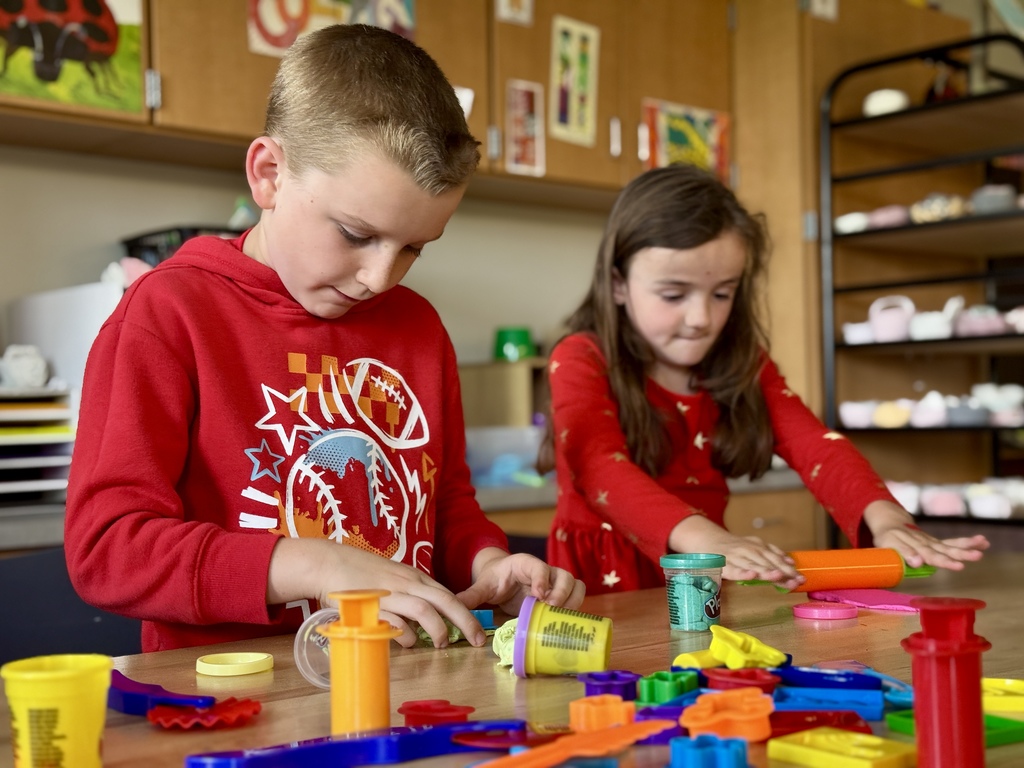 Two young students at a table playing with PlayDoh.