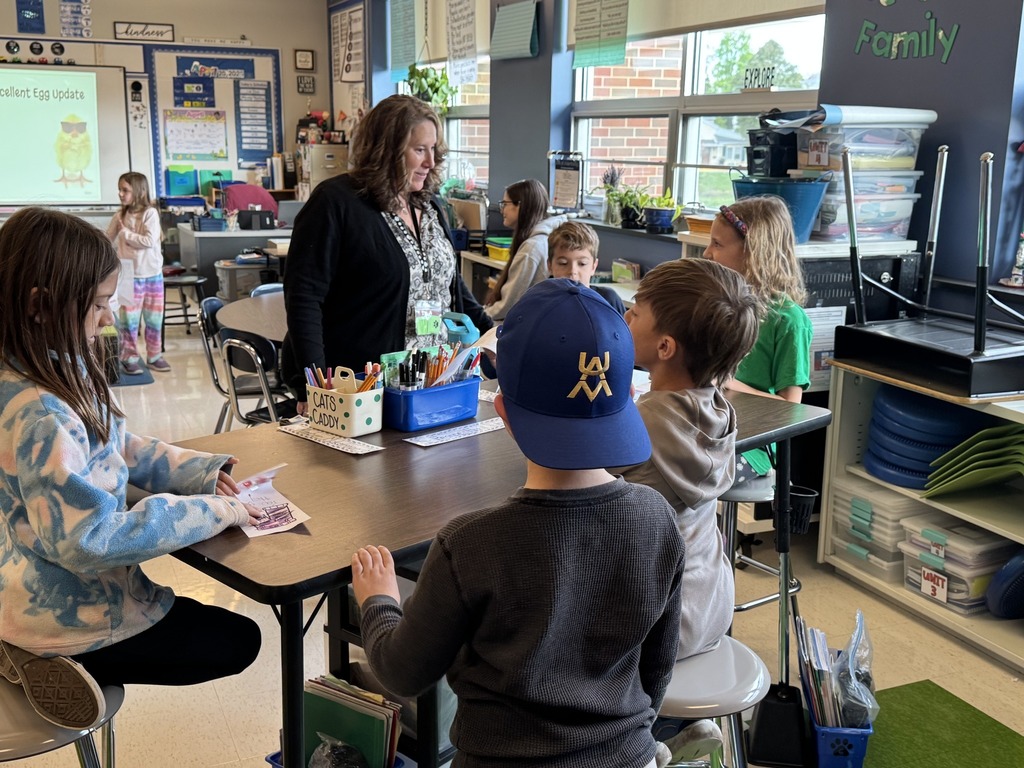 A teacher talking with a group of students sitting at a table.