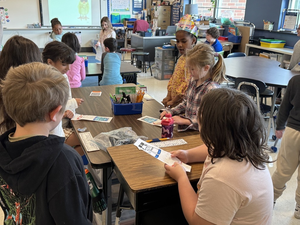 Students sitting at a table writing and coloring notes for older students.