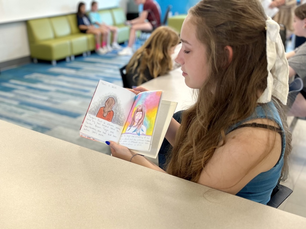 A student reads a self-written biography to young children.