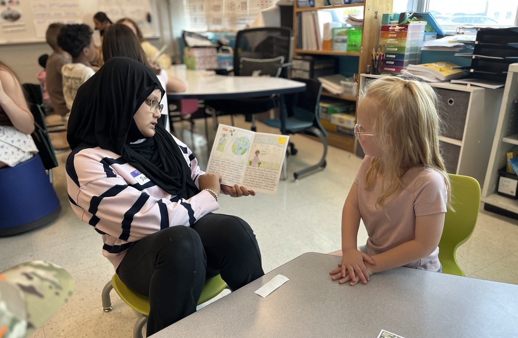 A student reads a self-written biography to young children.