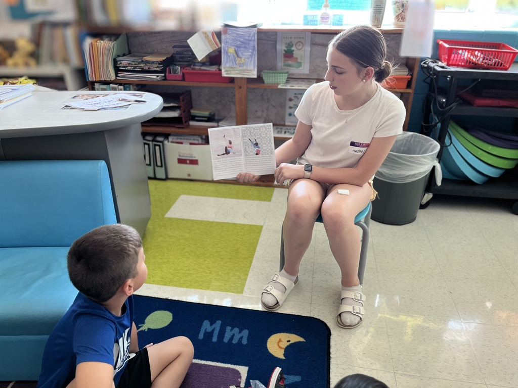 A student reads a self-written biography to young children.