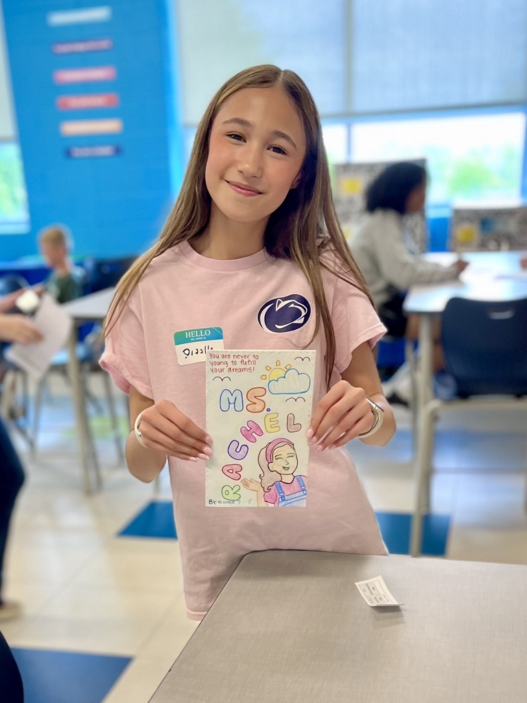 A student shows the cover of her self-published biography that she read to younger students.