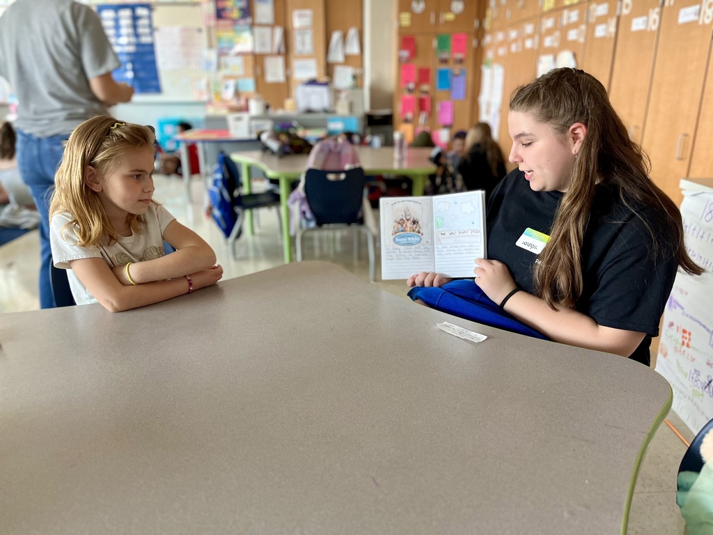 A student reads a self-written biography to young children.