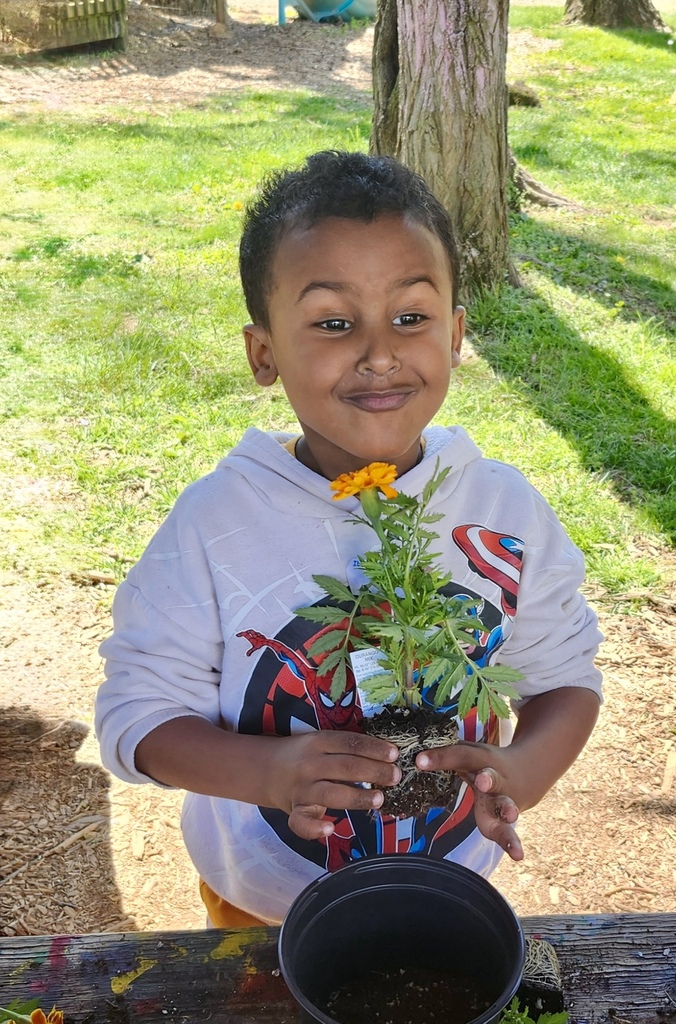 A young student smells a flower.