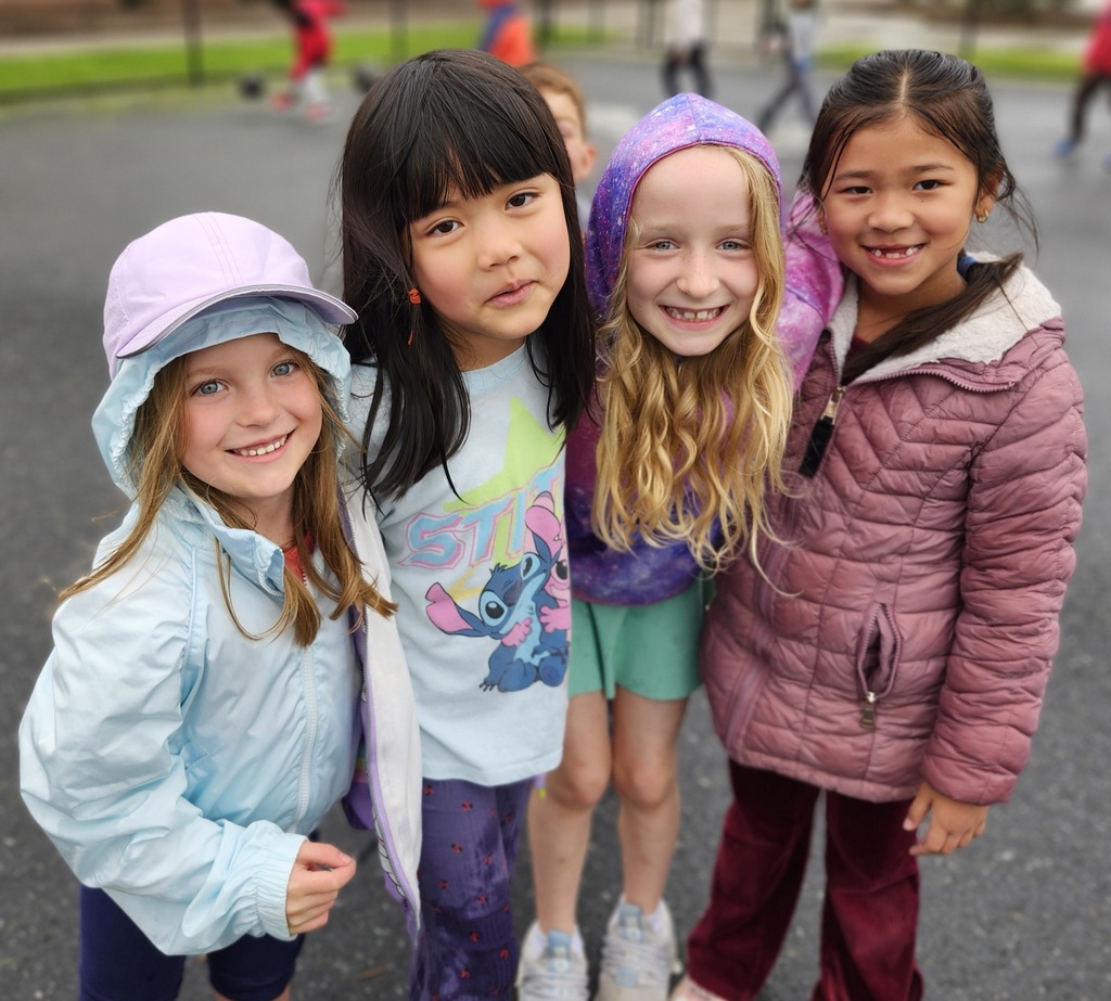 Friends on a playground smiling together for a photo while standing arm in arm.