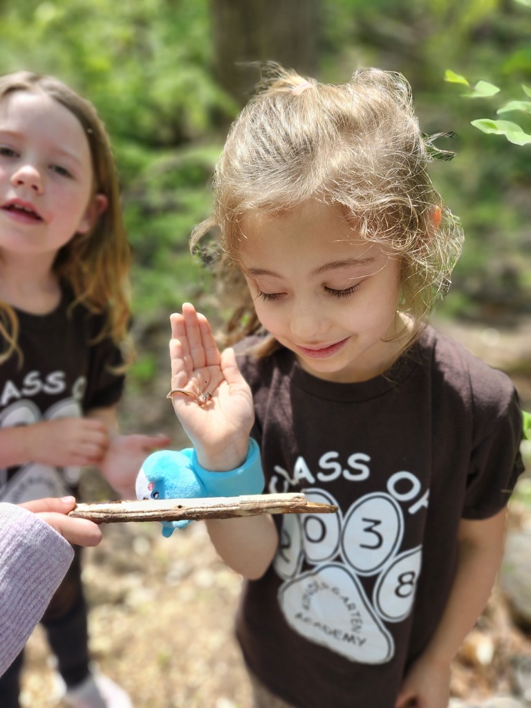A young student holds an insect in her hand.
