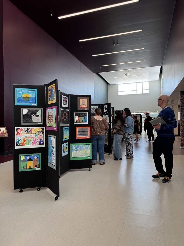 A group of adults looking at artwork lining a hallway.