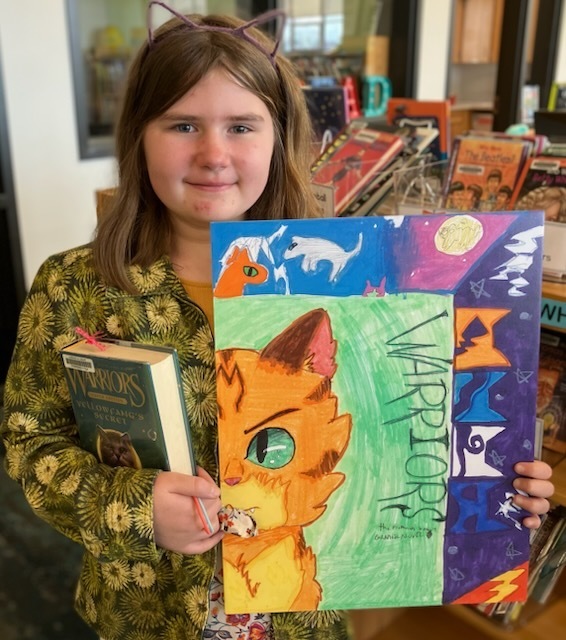 A student shows her handmade artwork that will hang in a school library.