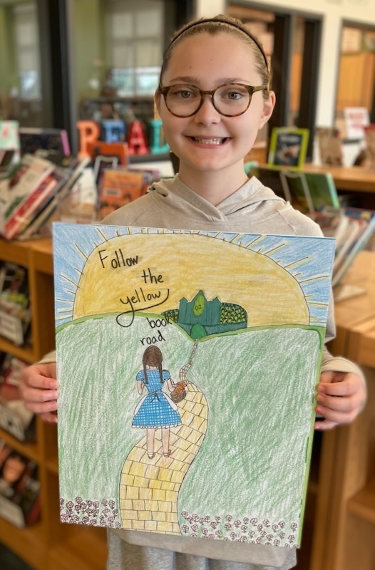 A student shows her handmade artwork that will hang in a school library.