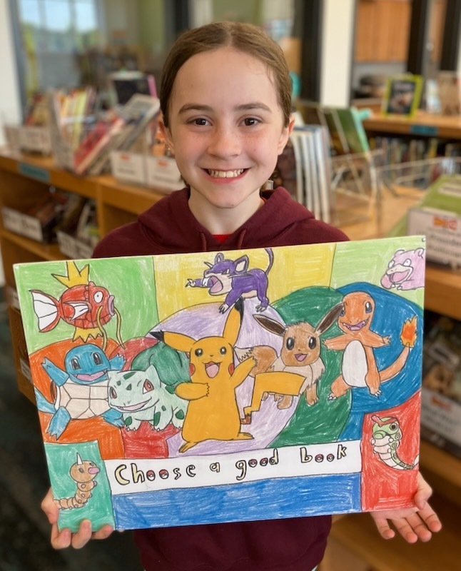 A student shows her handmade artwork that will hang in a school library.